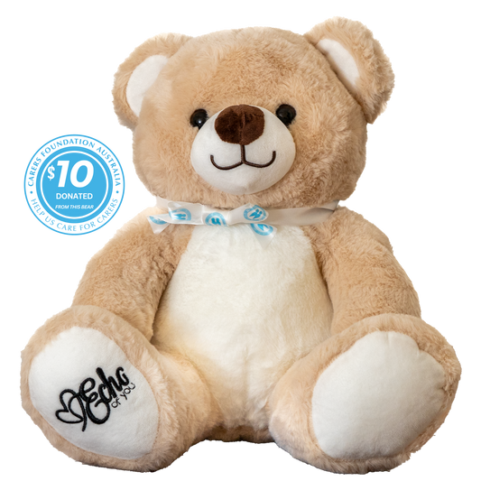 Plush teddy bear with a bow tie and a visible donation label on a white background